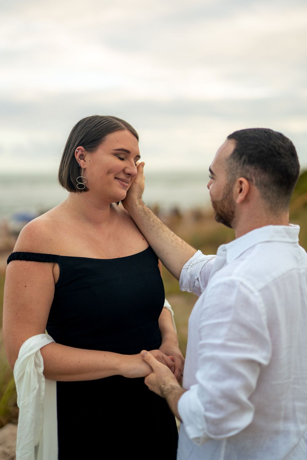 Emotional engagement moment captured near coastal lighthouse.
