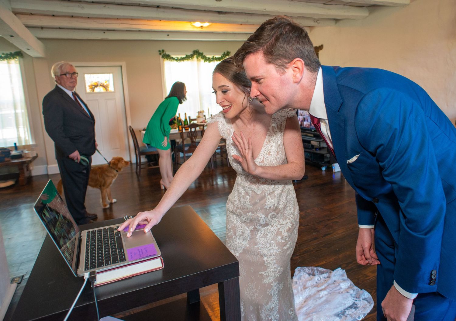 Wedding couple looking at laptop screen together during reception celebration.