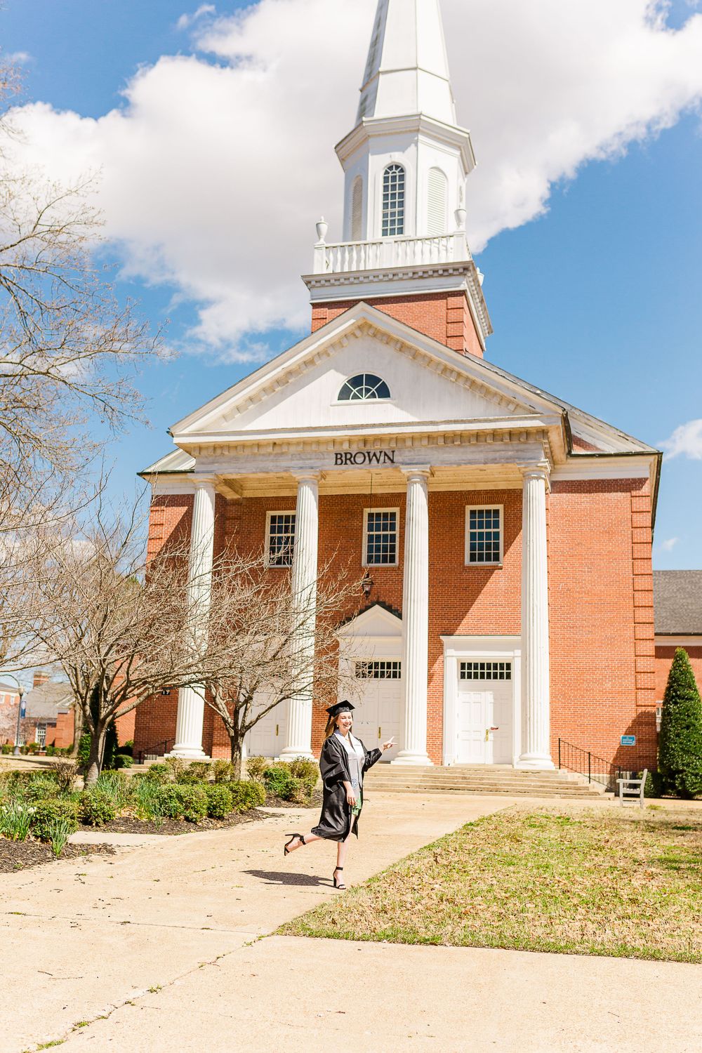 Red brick church with white steeple and columns on a sunny day.