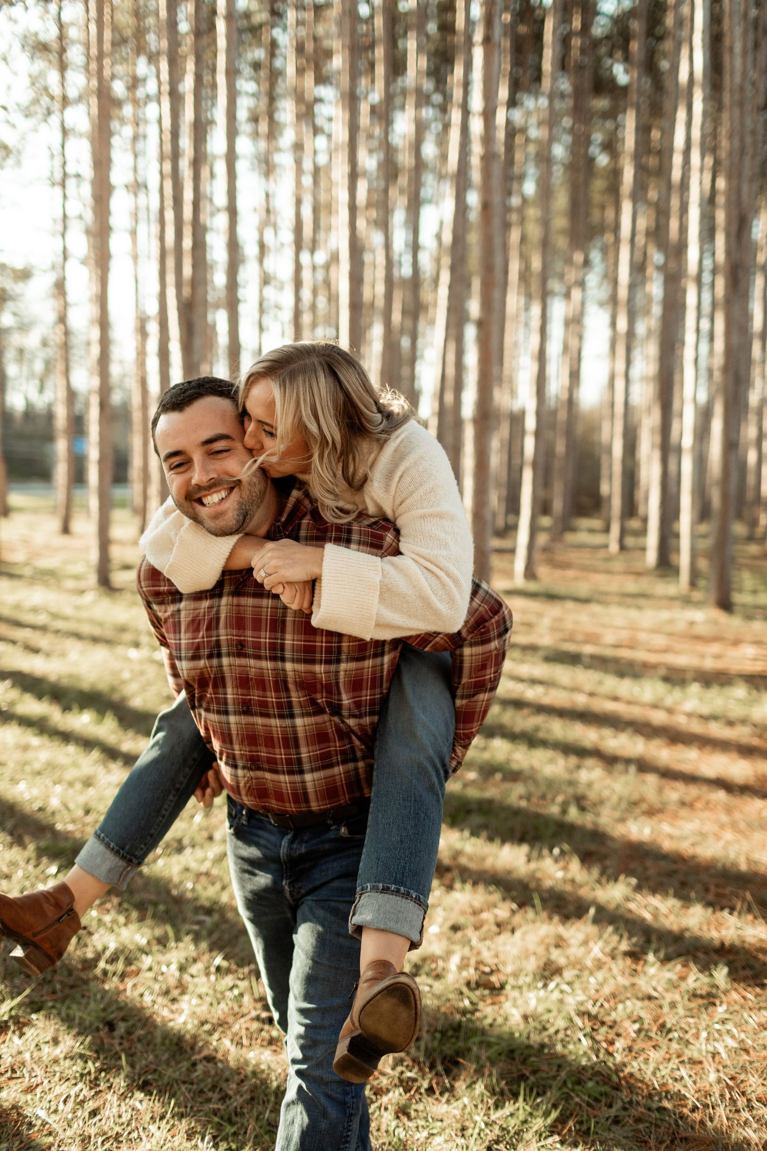 A playful piggyback ride in a sunlit forest with tall pine trees in the background.