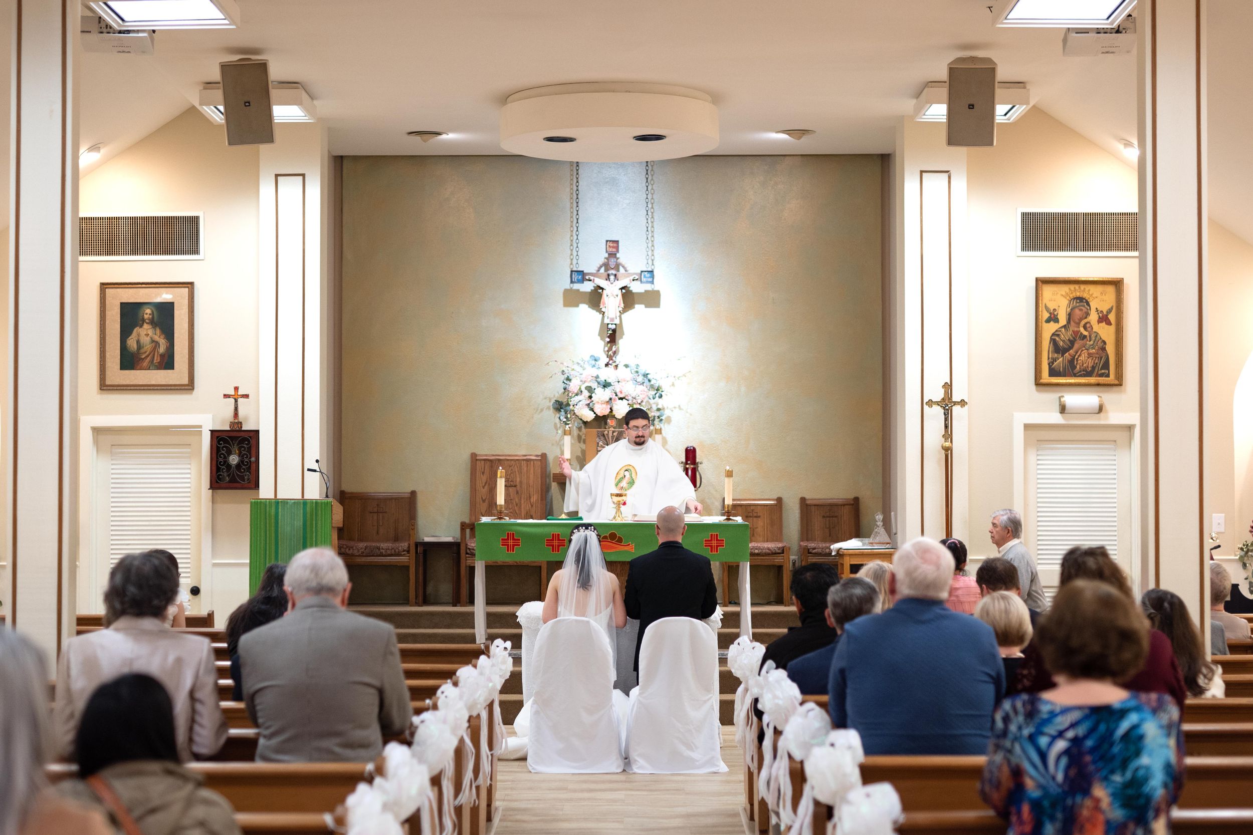 Interior of church sanctuary with white pews and altar prepared for wedding ceremony.