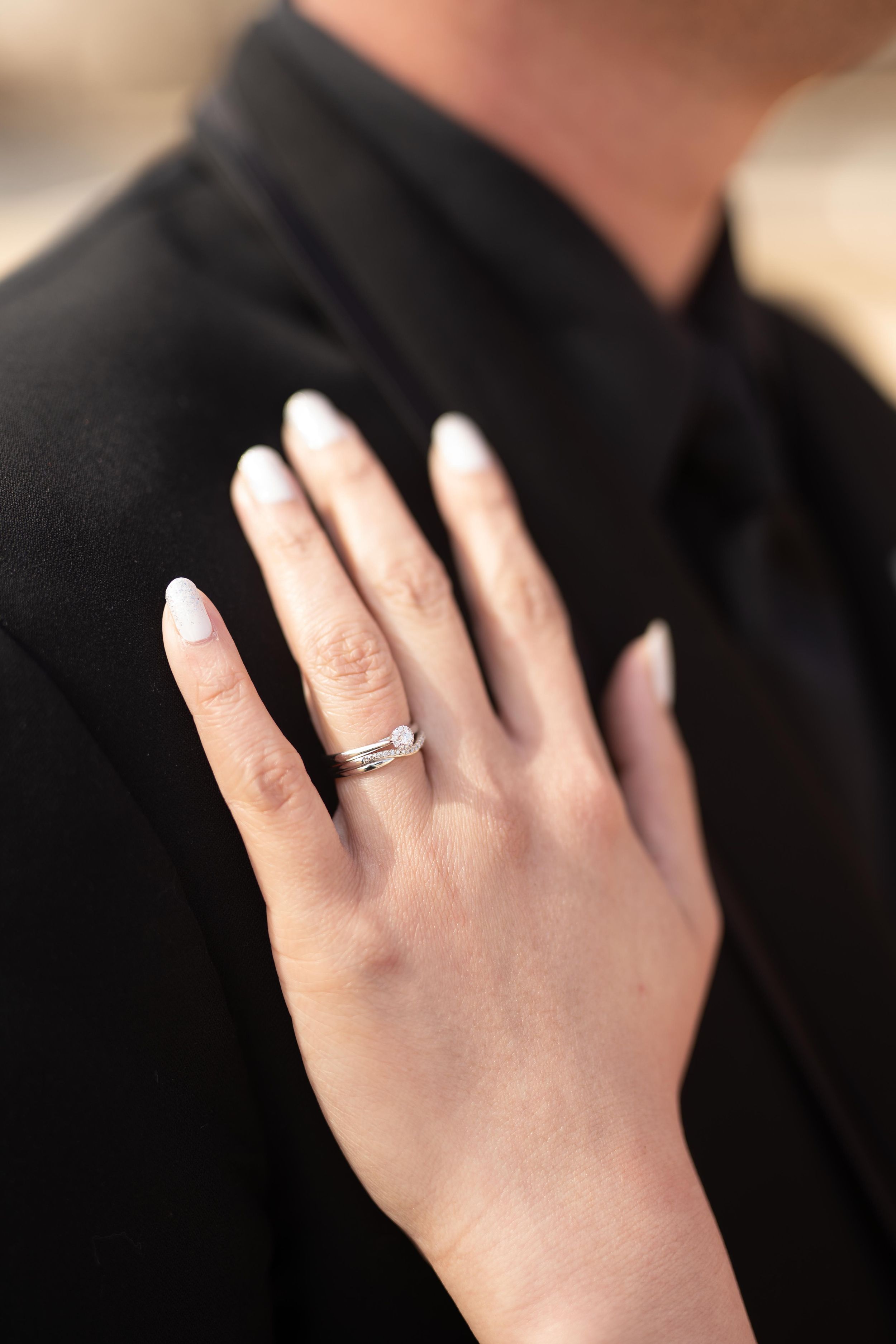 Close-up of wedding ring on hand against black formal attire.