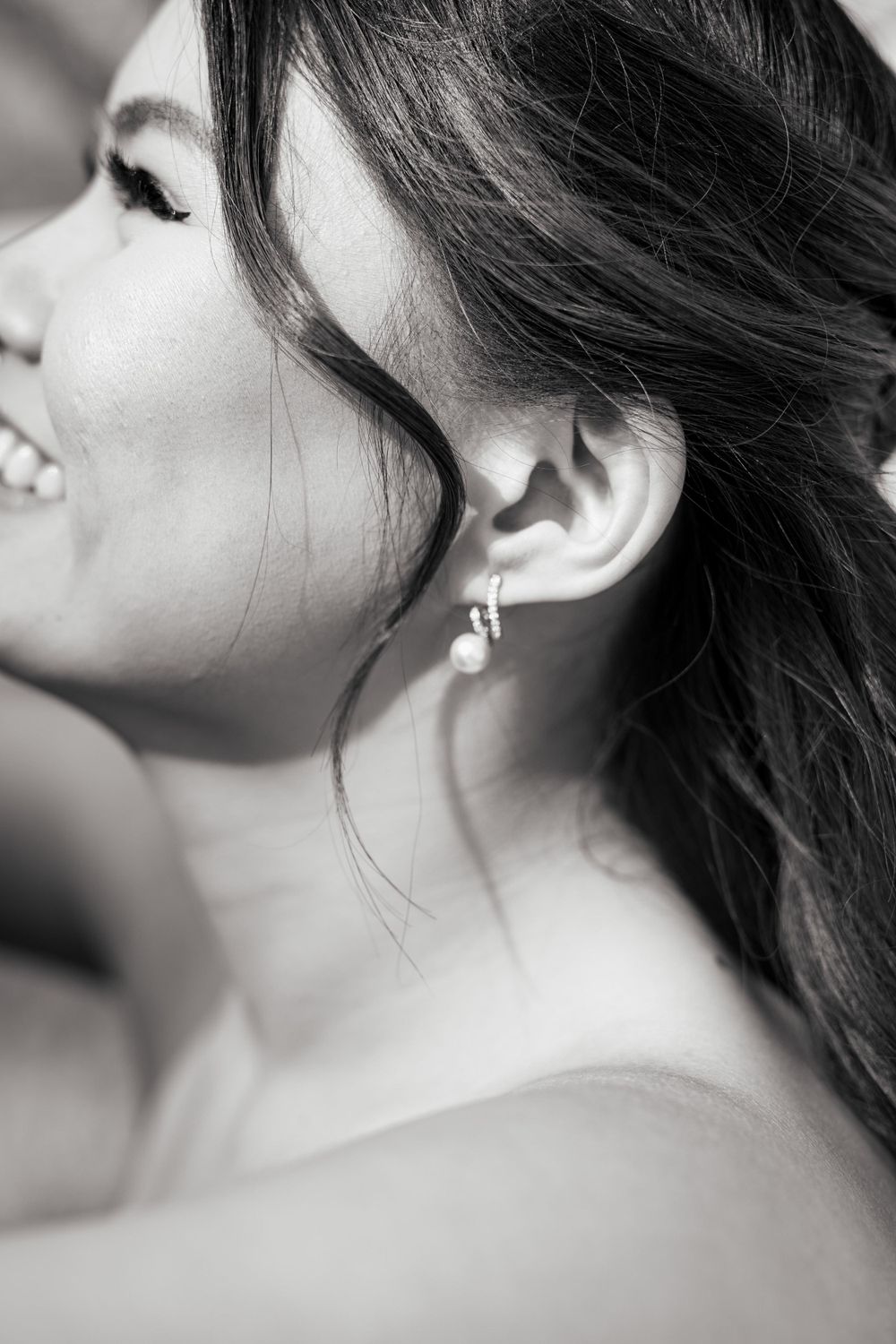 Black and white close-up profile portrait showing soft smile and delicate earring.
