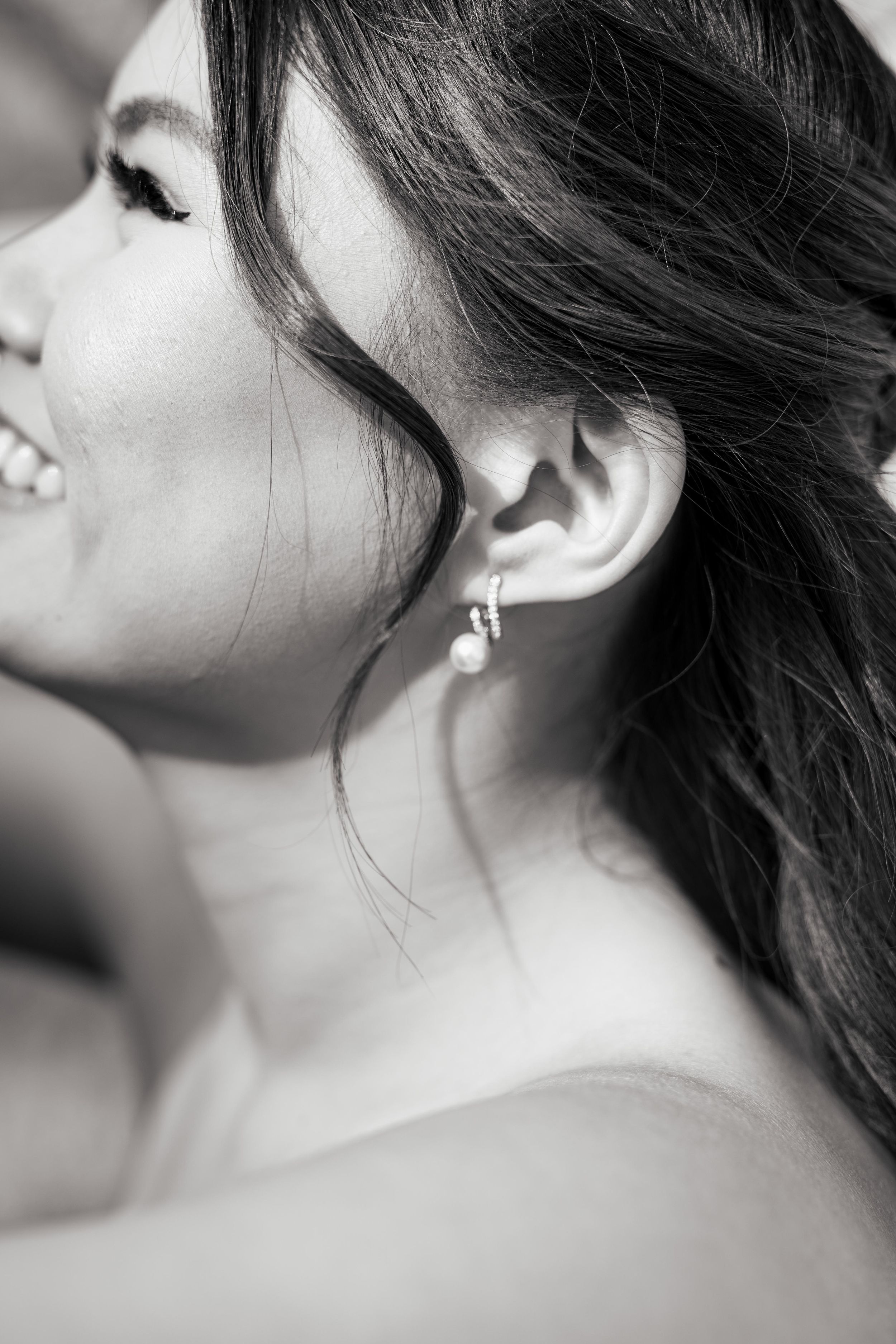Black and white close-up profile portrait showing soft smile and delicate earring.