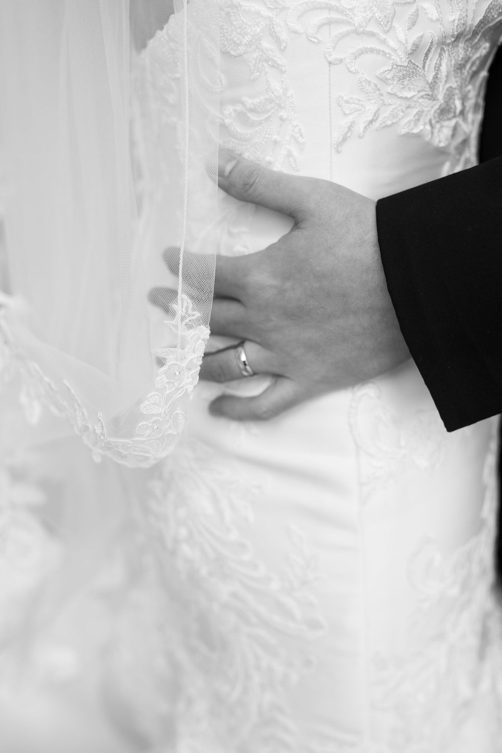 Close-up detail of hand holding lace wedding dress.