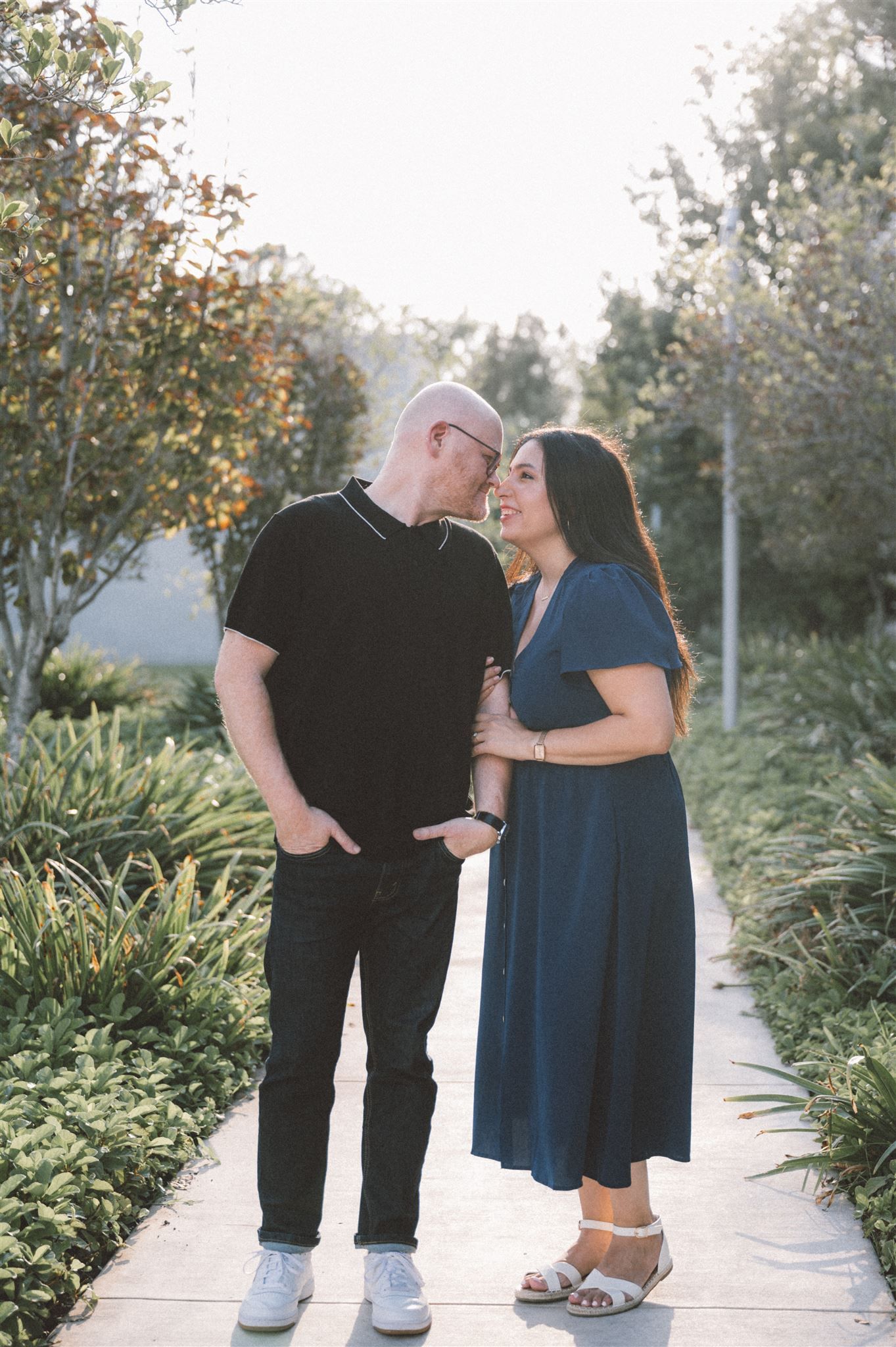 A couple shares a loving moment while standing on a garden pathway.