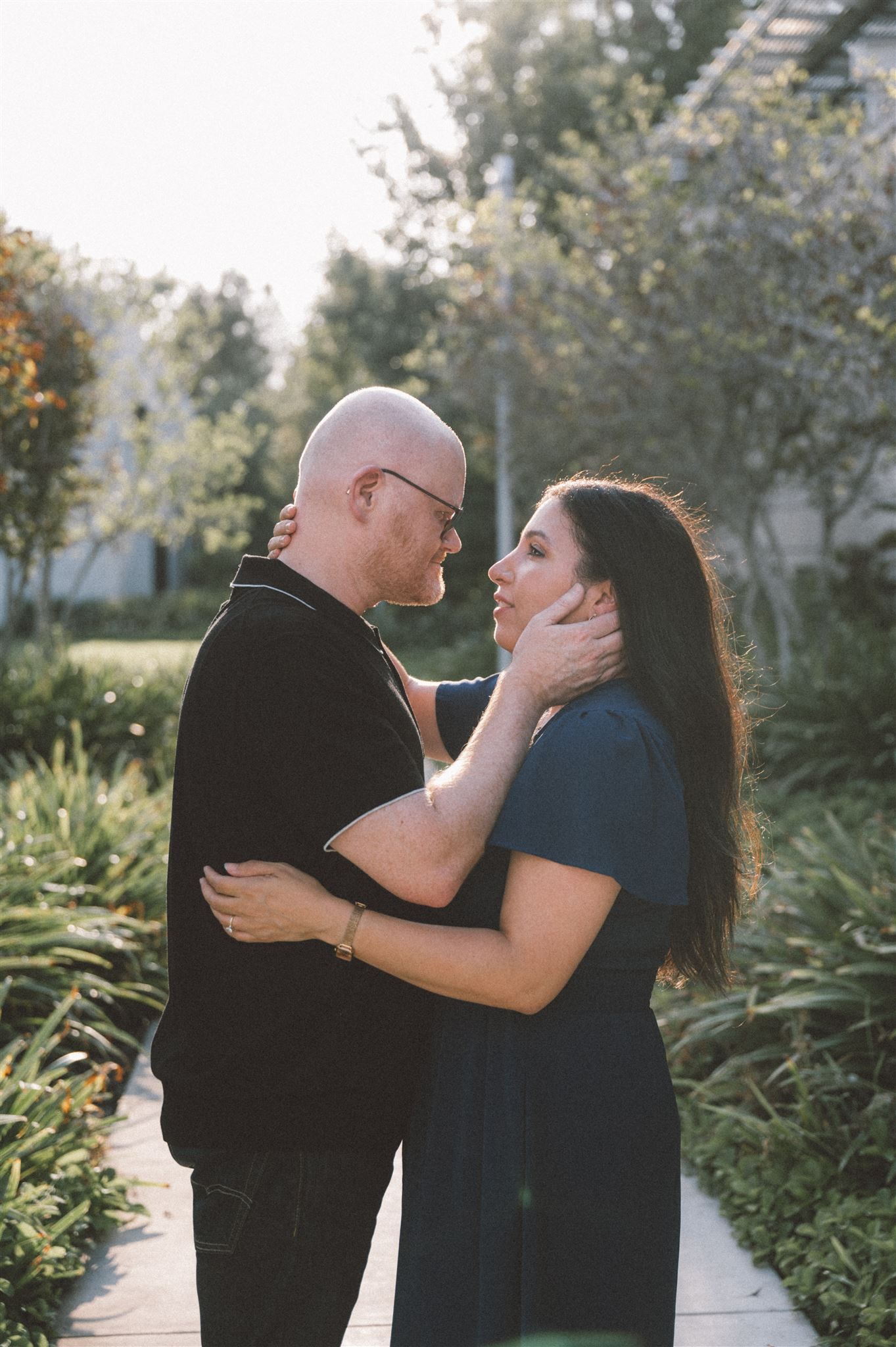 A couple shares an intimate moment in a lush garden setting during golden hour.