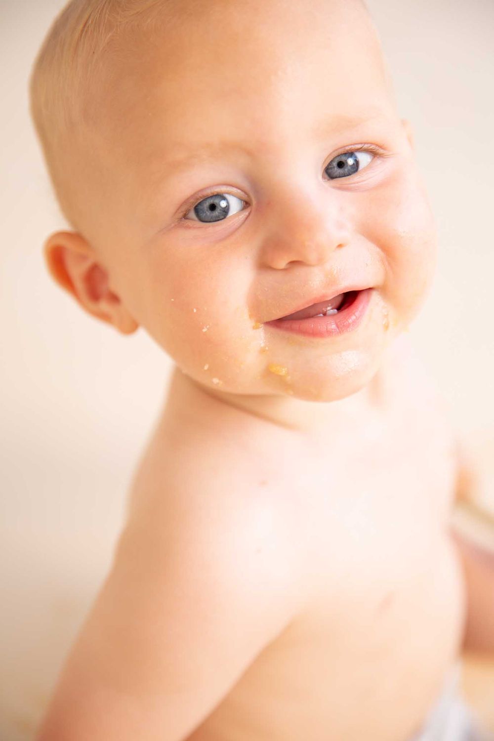 Close up portrait of smiling baby with cake crumbs on face.