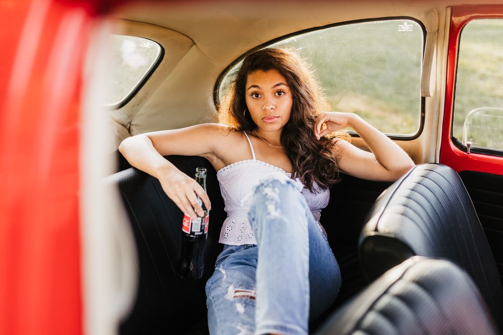 A casual lifestyle portrait taken inside a vintage red car interior.