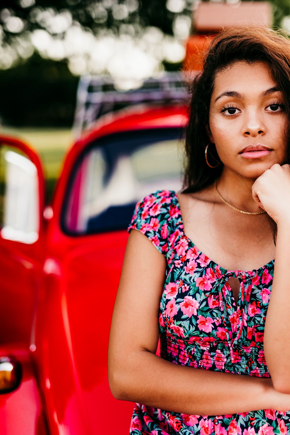 A stylish portrait featuring a red classic car in the background during sunset.