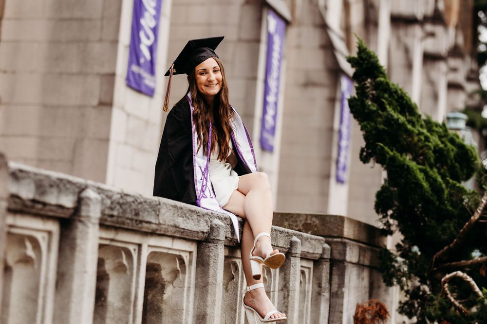 A graduation photo captured at a historic university building with gothic architecture.