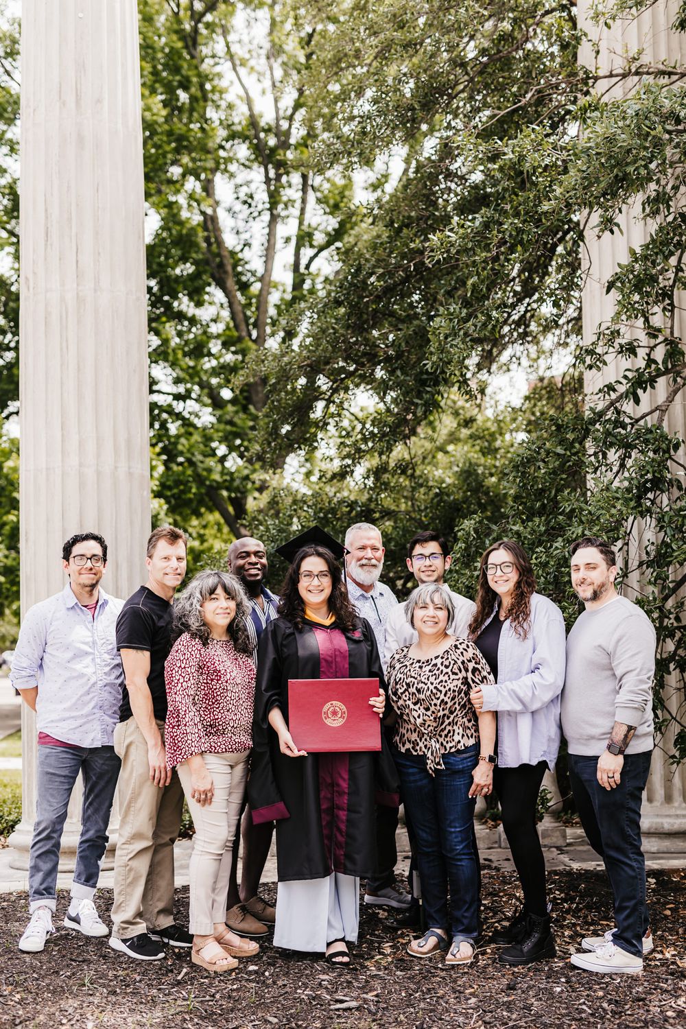 A graduation celebration group photo in front of white classical columns.
