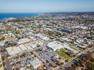 Wide aerial view of coastal suburban area with commercial buildings and residential streets.