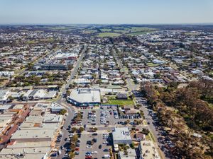 High altitude aerial shot of suburban commercial district with parking lots and surrounding neighborhoods.