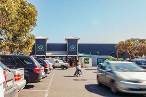 Large retail parking lot with cars under blue sky and trees.
