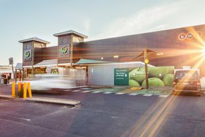 Retail storefront exterior at sunset with parked cars.