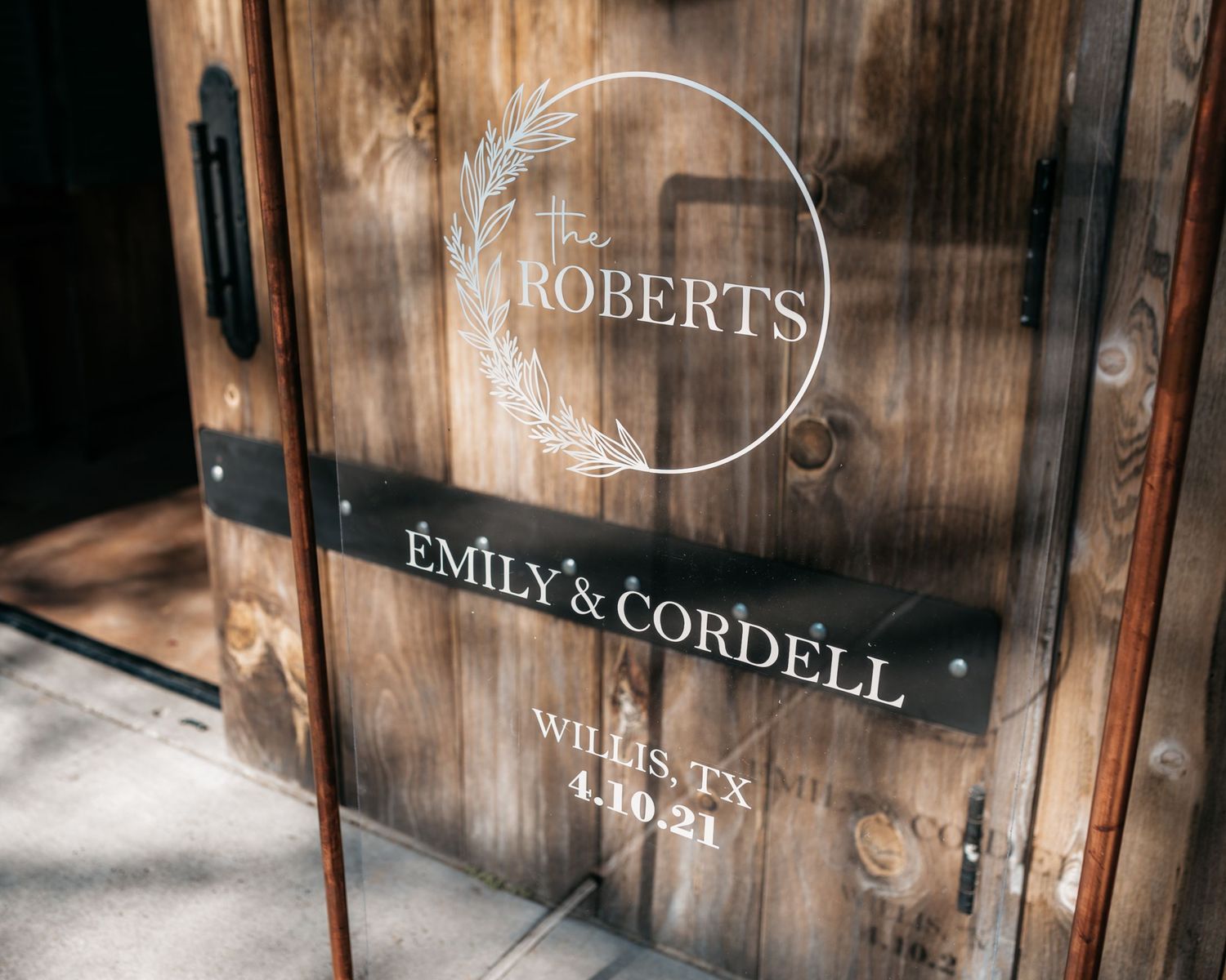 Wooden sign displaying 'Roberts' and 'Emily & Cordell' text with an elegant circular wreath design.
