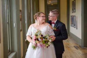Romantic wedding portrait in hallway with bride holding colorful bouquet.