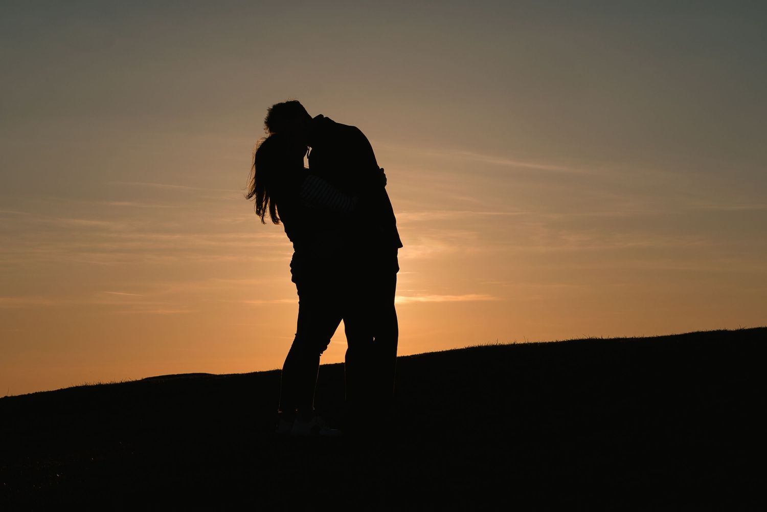 Silhouette of a young couple having a kiss at golden hour