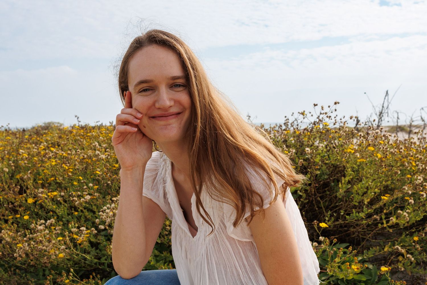 A candid moment captured in a field of yellow wildflowers on a bright sunny day.