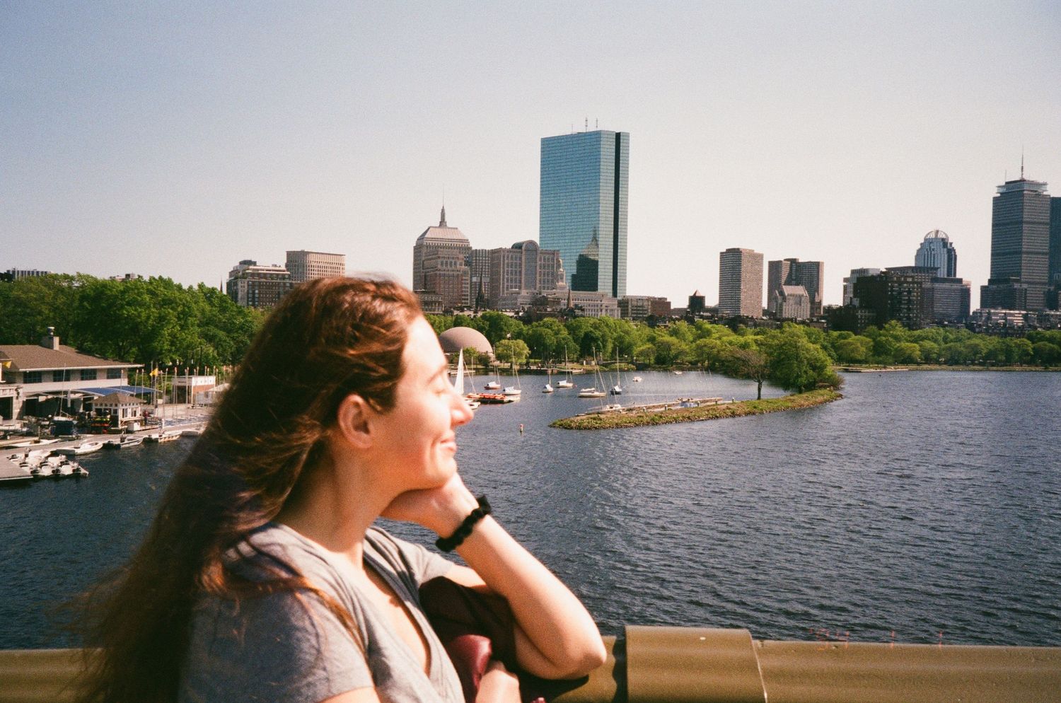 A scenic view of the Boston skyline across the Charles River on a sunny day.
