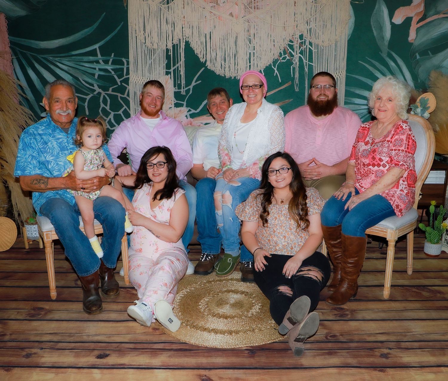 Extended family portrait in coordinated outfits against tropical backdrop with macrame decor.