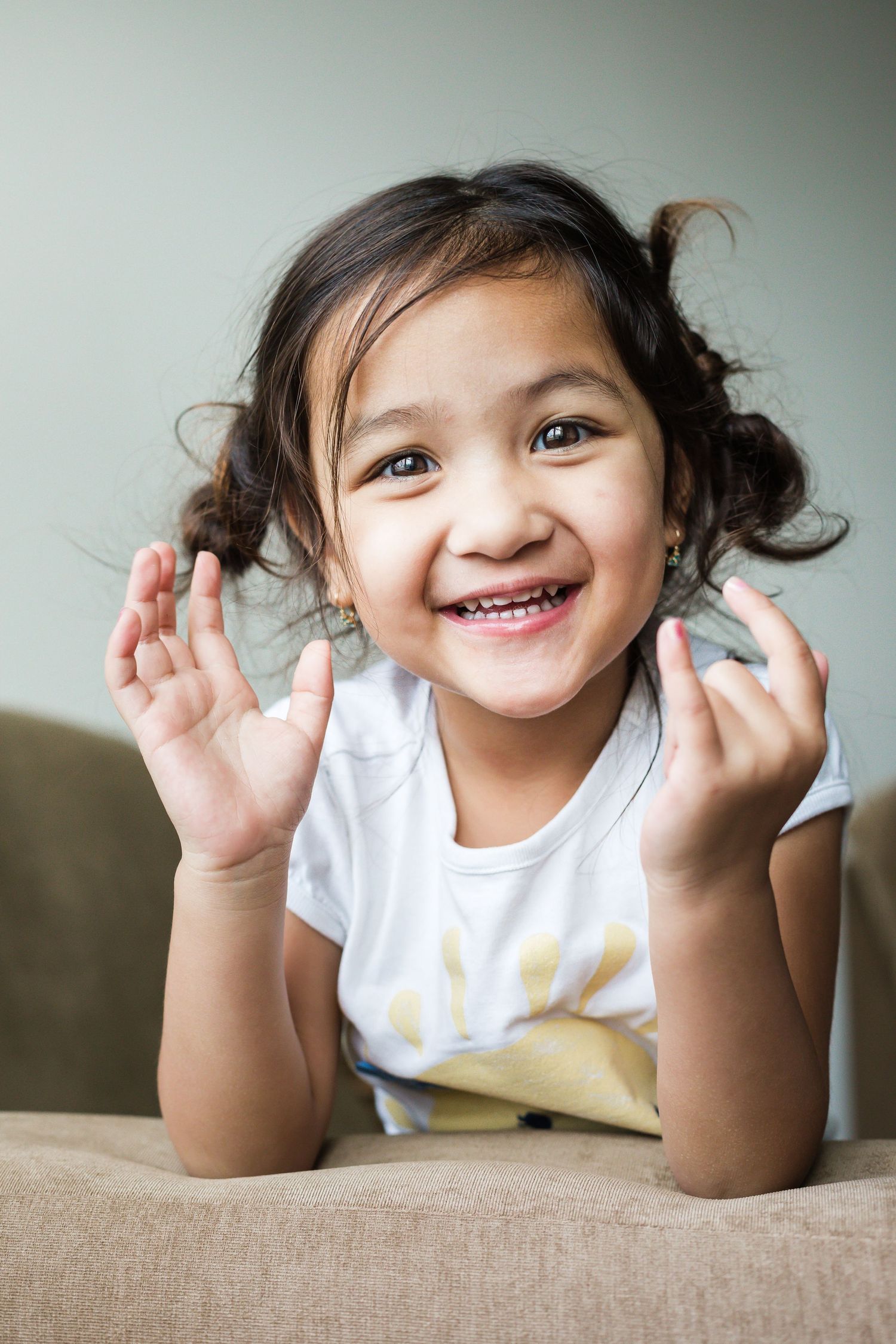 Excited little girl with brown hair and brown eye looking into the camera and smiling Anita Barcsa Photography
