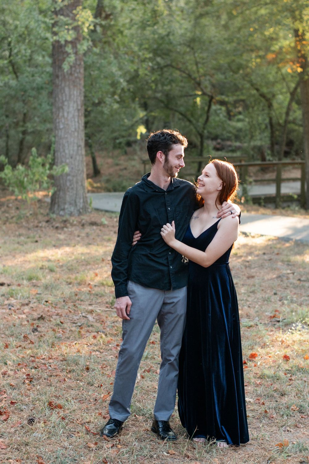 A couple shares an intimate moment on a wooded path during autumn.