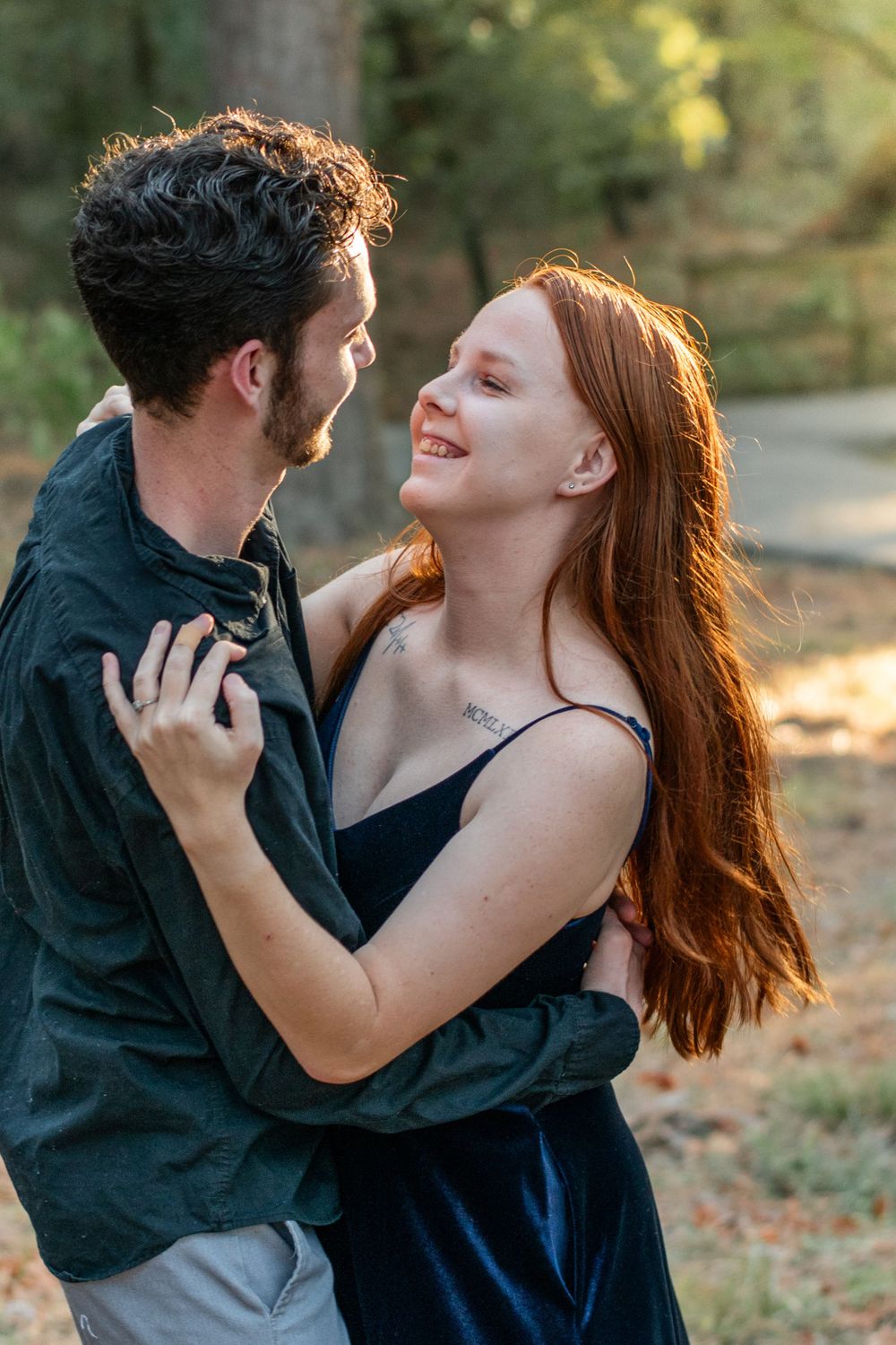 A romantic couple embraces during golden hour in an outdoor setting.