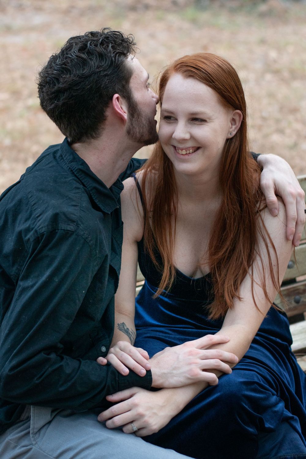 A tender moment shared between a couple sitting outdoors in casual formal wear.