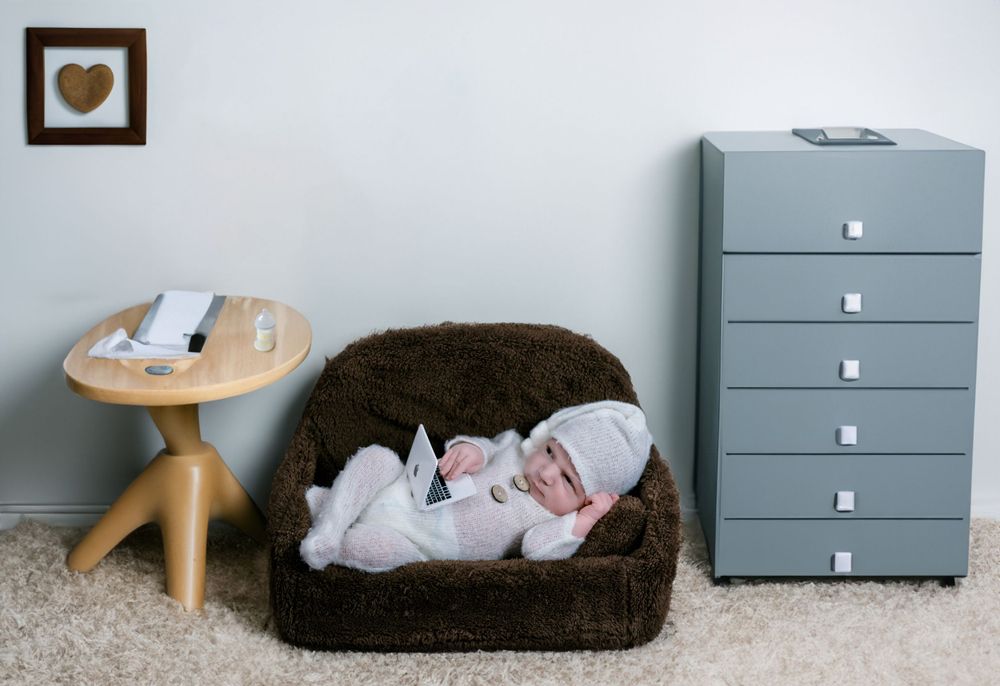 Minimalist studio setup with grey storage drawers and furniture for newborn photography.