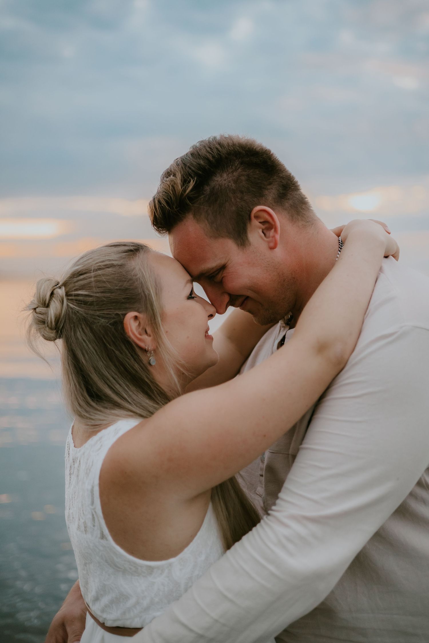 A romantic embrace between a couple against a sunset backdrop.