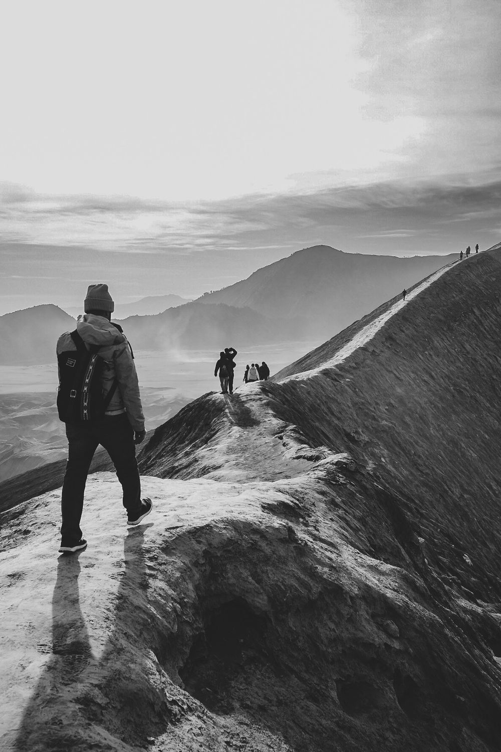 Hikers standing on a misty mountain ridge looking at dramatic landscape views.