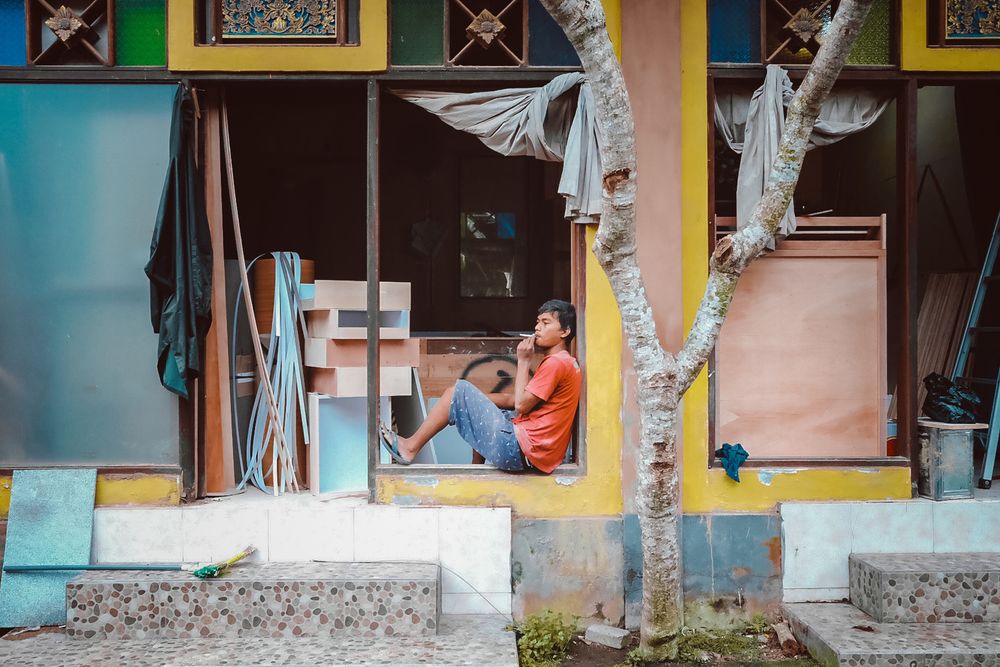 A colorful building facade with someone relaxing in a vibrant doorway.