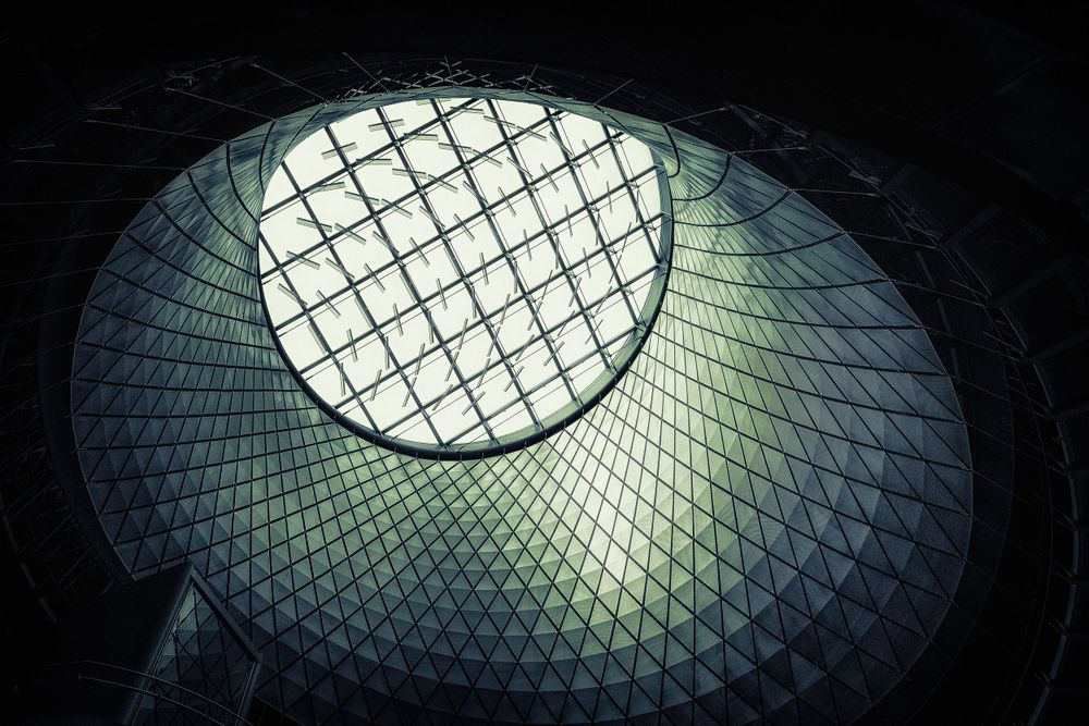 A geometric glass dome skylight with crisscrossing metal framework viewed from below.