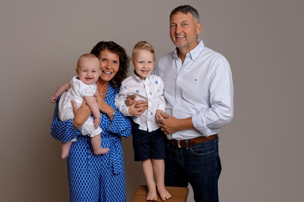 Studio family portrait with children in coordinated blue and white outfits.