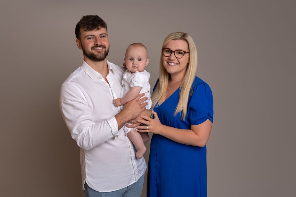 Studio portrait of family in white and royal blue against neutral background.