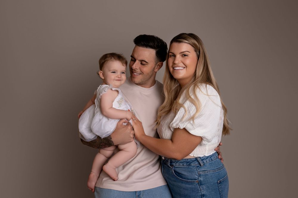 Intimate family portrait featuring coordinated neutral tones and natural expressions.