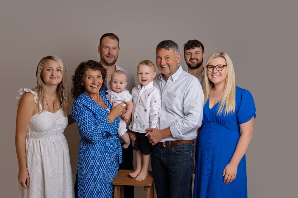 Extended family group portrait with multiple generations in coordinated blue and white attire.