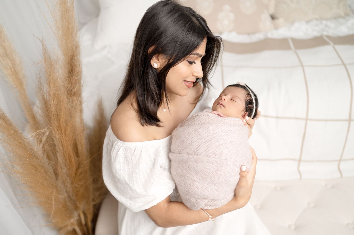 Intimate portrait of mother gazing lovingly at swaddled newborn in natural light setting.