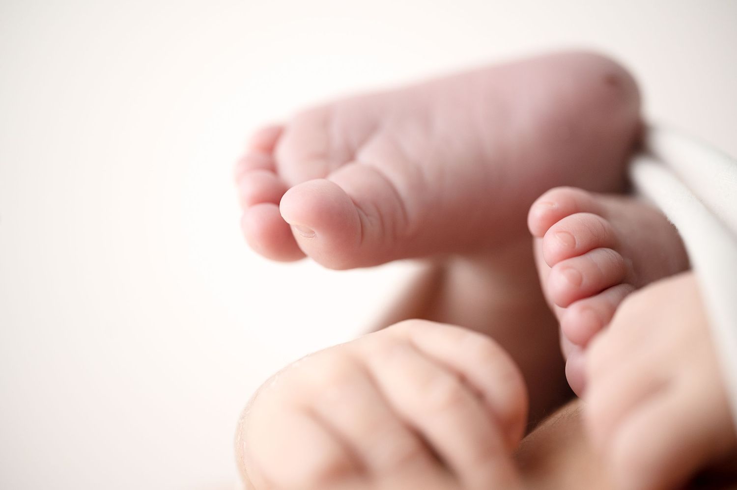 Close-up of tiny newborn baby feet showing delicate toes against soft background.