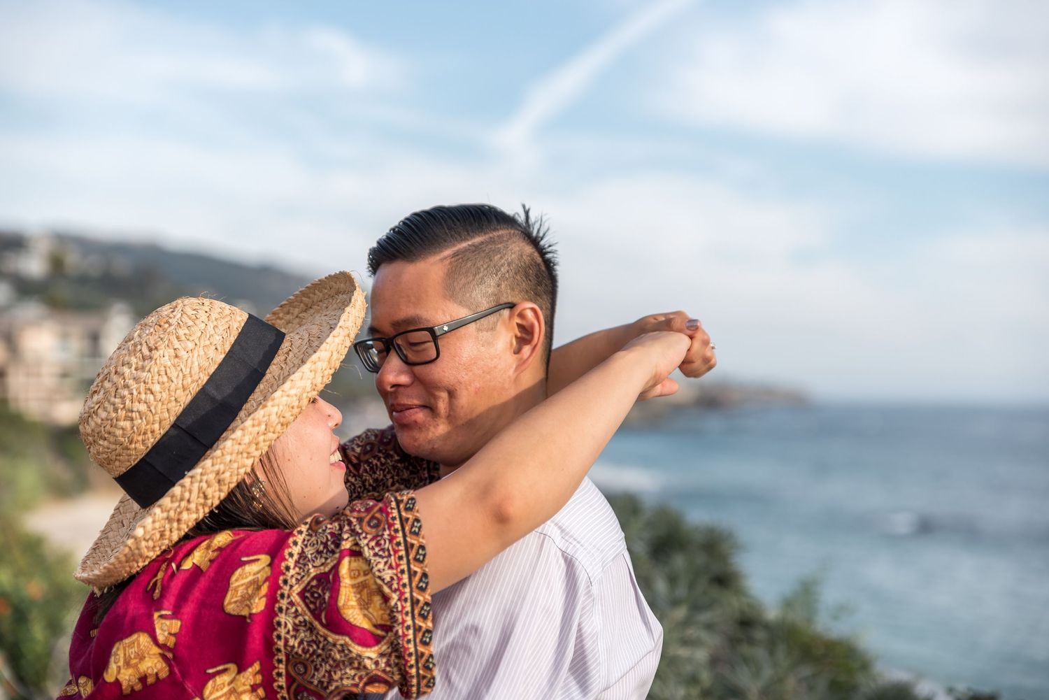 Couple embracing after a proposal, with the woman smiling and the man looking at her lovingly.