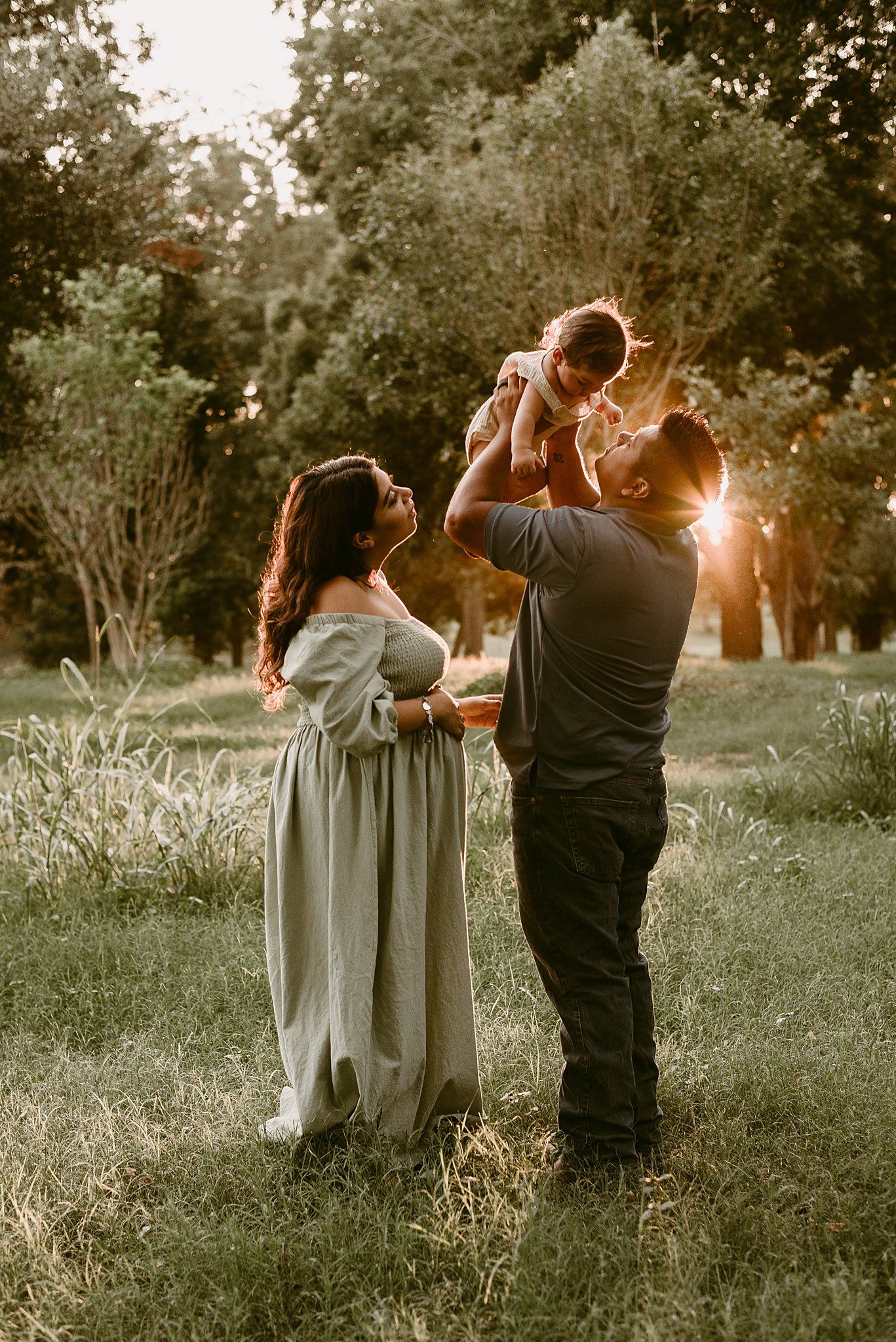 A tender family moment captured in backlit golden hour lighting at a park.