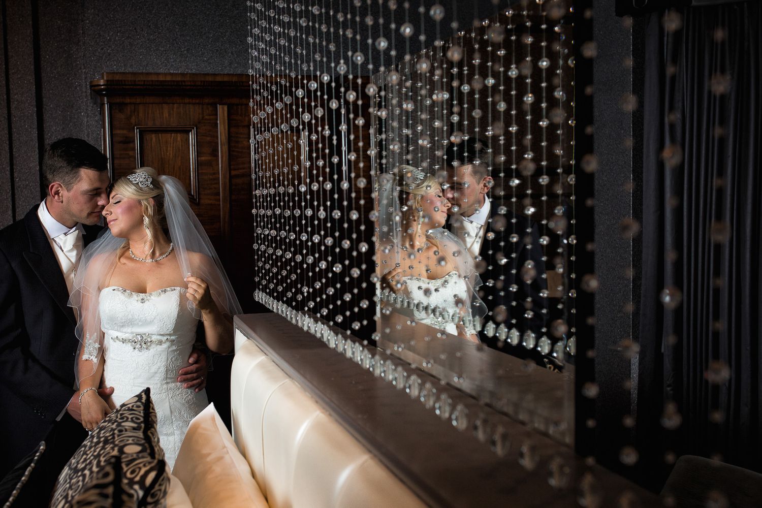 Intimate moment between bride and groom reflected in a bedroom mirror on their Abbey house wedding day