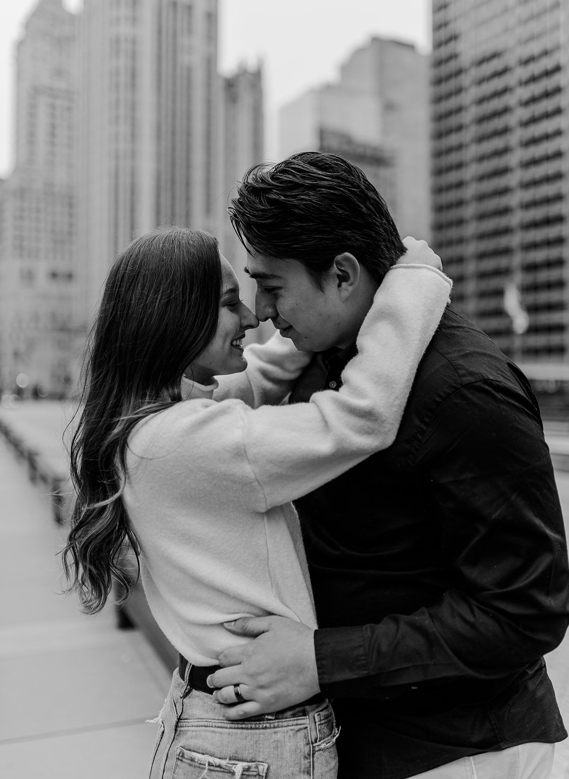 Romantic urban couple embracing against city skyline backdrop in black and white photography.