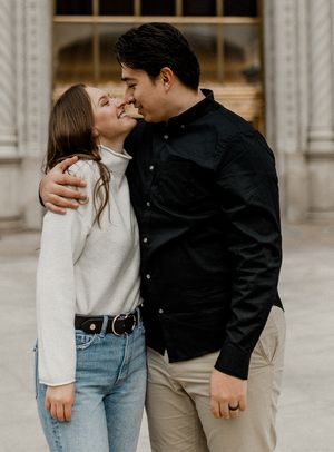 Couple sharing intimate moment outside classic architecture building.