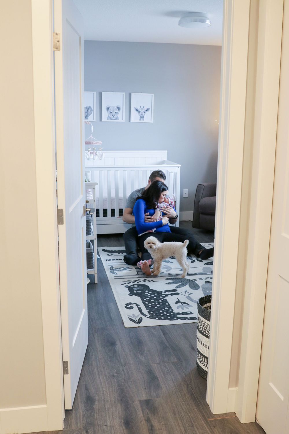 A woman is sitting in a room with a baby and a dog.