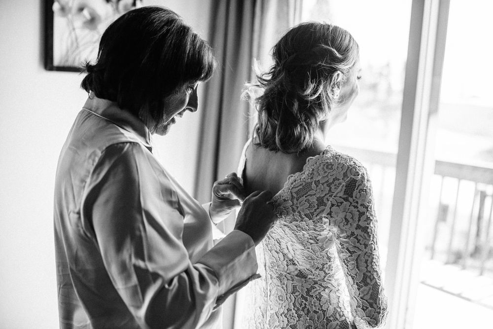 mom helping bride zip up her dress, black and white photo