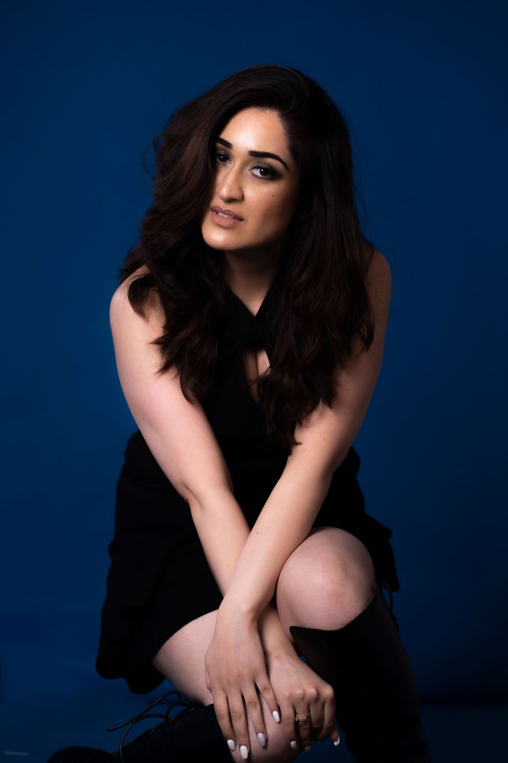 A moody portrait against blue background shows a woman in black dress with flowing dark hair.