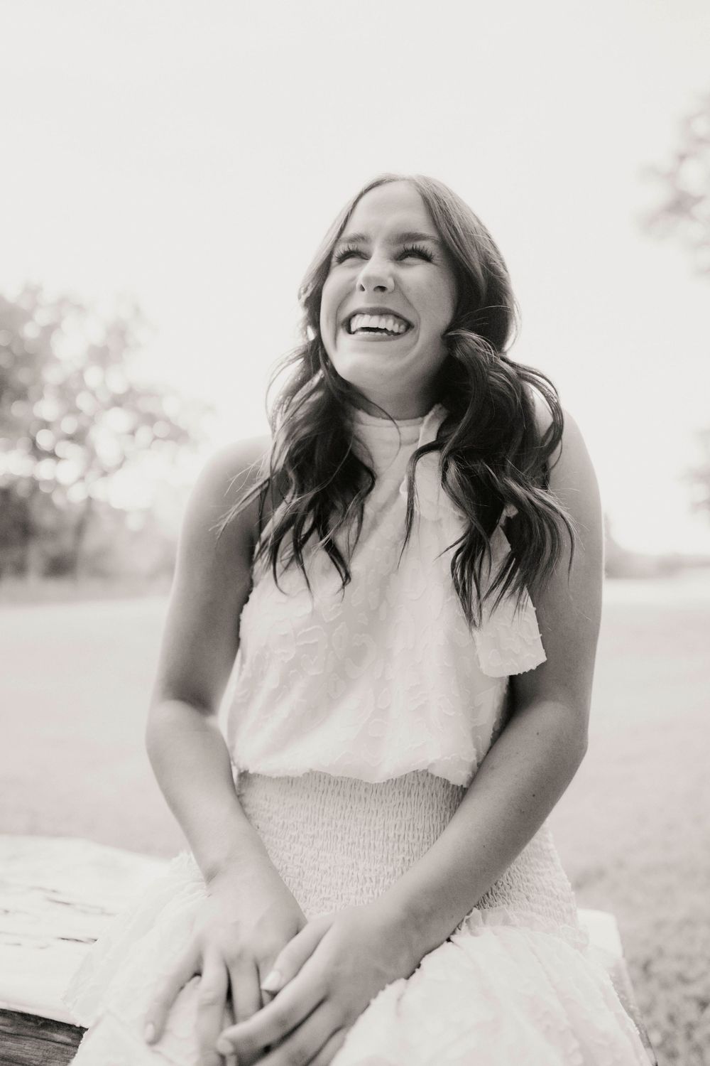 Black and white portrait showing joyful laughter in natural outdoor setting.